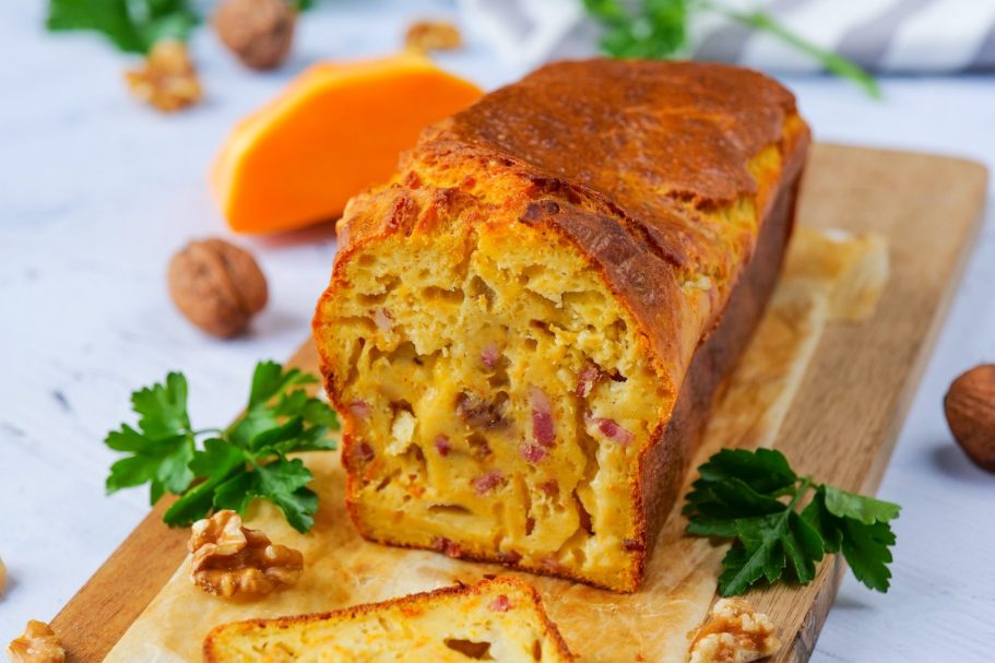 Cake du moment Gâteau aux légumes avec noix, tranché sur une planche en bois, décoré de persil.